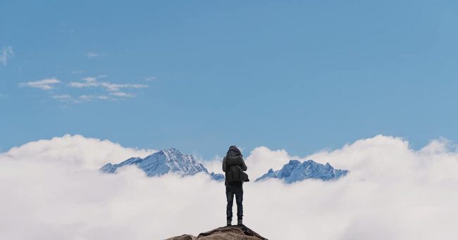 a man with backpack standing on mountain top, with snow mountain Social distance in the age of social media